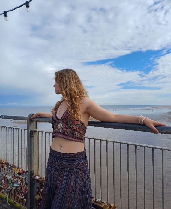 Picture of Poppy Willow standing in front of a gate and looking back at the sea