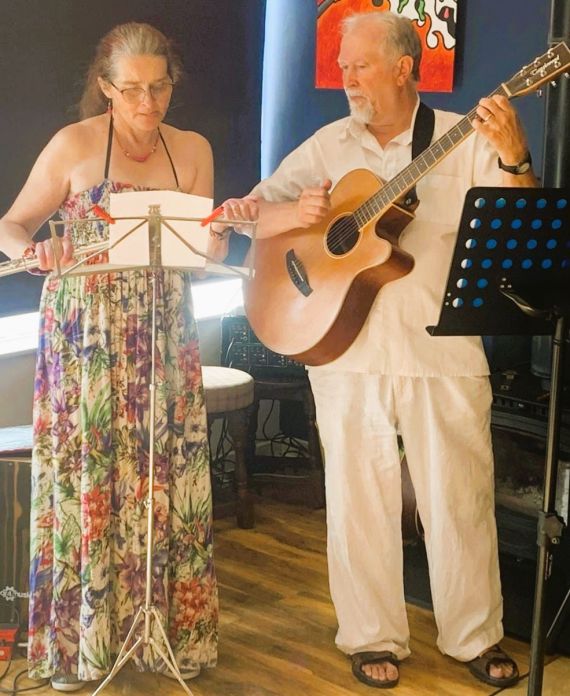 Sybille (right), and Ian (left) performing. Ian is holding a guitar.